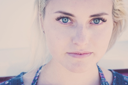 defocused portrait with focus on clear eye of a beautiful caucasian russina girl model young sit down and looking to you on camera. little smile relaxed for lifestyle conceptの写真素材