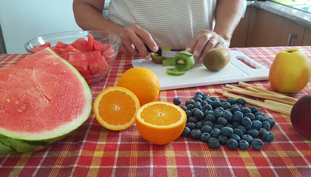 elderly woman cutting raw fruit for an healthy saladの写真素材