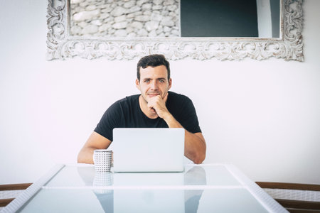 portrait of beautiful young man caucasian at work with a laptop computer on a desktop in a bright...