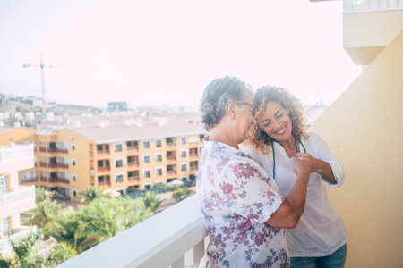 couple of women friends stay in the terrace together enjoying the friendship at home touching punch in real friendly way.の写真素材
