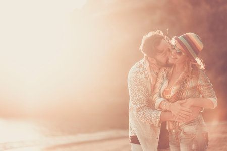 couple in love man and woman having fun with love and kisses during the sunset time. sunlight and warm colors filter and life forever together concept. hug and smile for beautiful people outdoor. beach and backlightの写真素材