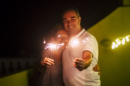 Celebrate concept with couple man and woman with light sparkles fire by night together in friendship and relationship. Closeup and new year eve concept party celebratingの写真素材