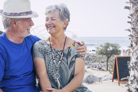 Happy senior couple laughing hugged on a summer day. concept of vacation, relaxation, rest. Blue sea in background. White clear sky and cheerful seniorsの写真素材