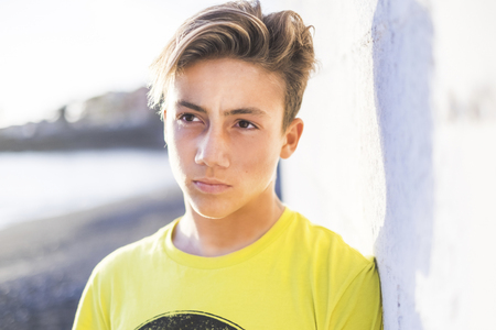 young beautiful male teenager smile outdoor with a blue sky background. summer style concept imageの写真素材