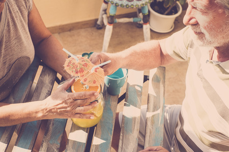 couple of elderly people drink together on the terraceの写真素材