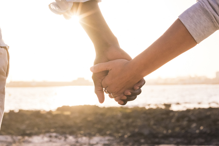 Diversity and no racism concept image with female and male hands taking each other with love and friendship. caucasian and african race together at the beach for peace and love image future hopeの写真素材