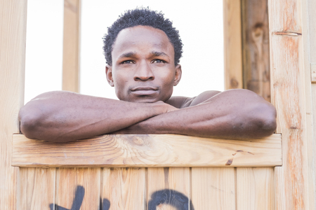 Cheerful and happy relaxed black man afro race rest and look away. beautiful face and skin and eyes for a nice man portrait in outdoor with white background bright skyの写真素材