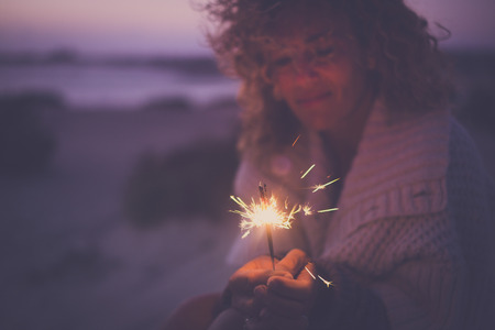 Single attractive woman defocused portrait taking alone sparkles light fireworks to celebrate new year or party event outdoor in alternative way with no friends around - sad and happy conceptの写真素材
