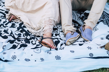 couple of hippy chic caucasian people lay down on a ethnic designed pareo with bright clothes and dress in outdoor leisure activity togetherの写真素材