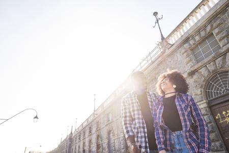 happy couple enjoying outdoor leisure activity together like boyfriend and girlfriend in young love adventure. city urban place and sunny day with sun in backlight. laugh and smile and have fun.の写真素材