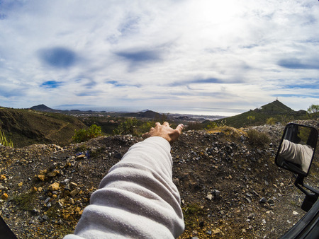 Man's arm outside car while driving and enjlying the nature and the mountains landscapo outdoor - travel and discover country side scenic placesの写真素材