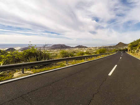 Long road in mountains country side place with valley and ocean in background - spring colours and travel transport concept with car vehicleの写真素材