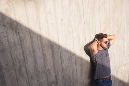 attractive young man standing  near some urban staris and looking at the sun. shadow and light composition for attractive people concept in the cityの写真素材