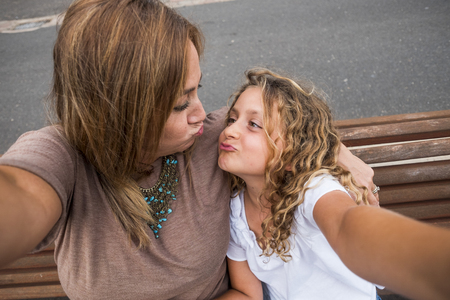 family couple mother and daughter together in outdoor happy leisure activity hugging and enjoying the day of summer before the back to school and the winter. blonde caucasian mom and girlの写真素材