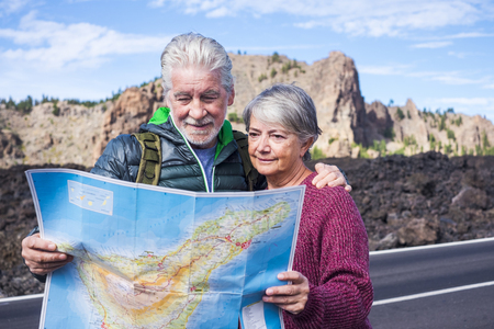 beautiful caucasian aged senior couple man and woman people traveling using old style paper map at the mountain - enjoy the lifestyle and retired life together with a backpack and needs of adventure and independenceの写真素材