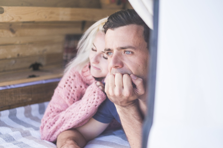 Beautiful young romantic couple lay down inside an old van together looking aoutside and resting or sleeping - romance scene and lifestyle for nice travelers who love the world and enojy lifeの写真素材