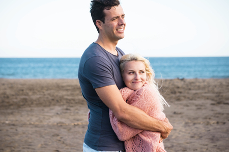 happy cheerful caucasian couple hug and love at the beach in outdoor leisure activity - friendship and relationship between young nice people - vacation and enjoying lifestyle conceptの写真素材