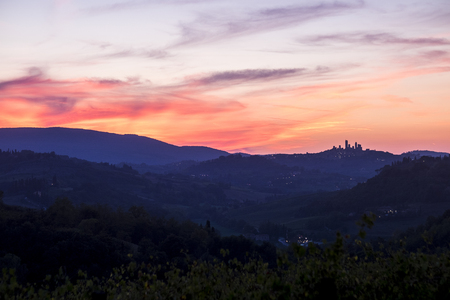 San Gimignano Tuscany view after a great coloured sunset in the beautiful wine valley in Italy. Colors red and blue and ancient town tower in silhouetteの写真素材