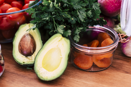 Green avocado for guagamole sauce with background of fresh seasonal vitaminc vegetables - vegetarian and vegan health food for wellness and diet conceptの写真素材