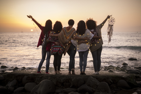 Dreaming image with group of females friends hug each other all together looking the sunset for friendship and love concept - Forever friends and dream lifestyle concept - people enjoying and feeling the life and the natureの写真素材