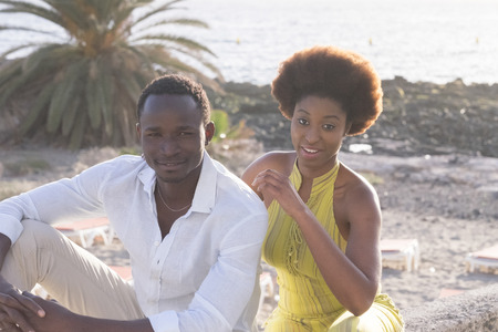 Afro black couple enjoying the outdoor leisure activity at the rocky beach during vacation - african style hair for the young woman and white shirt for the man - fashion conceptの写真素材