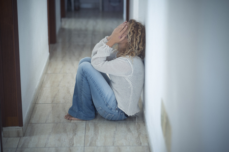 Lonley scared sad girl at home desperating and crying alone protecting face with the hands - stop violence in married life and protect female international dayの写真素材