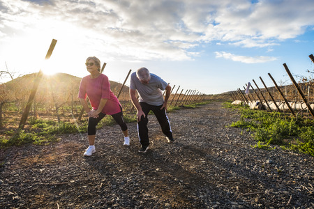 Couple of adult senior doing sport activity in the morning to stay healthy and life long time together - fitness and stretching for elderly society - people doing fitness activities outdoor conceptの写真素材