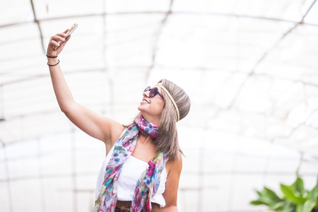 caucasian female take a selfie picture - addicted to social media network internet concept for nice cute people - outdoor leisure activity with modern technologyの写真素材
