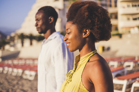 Black girl and boy young african people standing and smiling in summer day with sun beads in background. Beautiful young people portrait. Traditional rare afro hairの写真素材