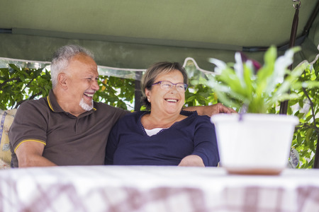 nice couple of beautiful caucasian senior 70 years old sit outdoor at home having fun with smiles and laugh. happy life together forever in love and enjoy retired time. focus on manの写真素材
