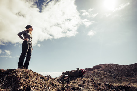 Young womn hiker standing and looking at the road during mountain trekking - tourism and adventure travel lifestyle concept - healthy people enjoying outdoor leisure activity - middle age female and natureの写真素材