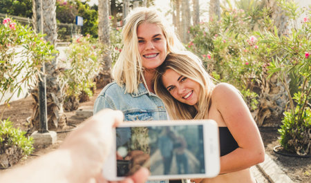 Couple of blonde girl smile and enojy the friendship while a friend take a picture to them - smiling...