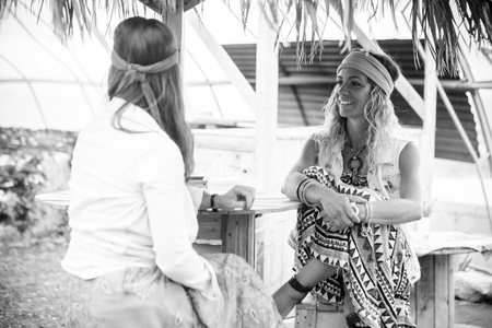 Black and white portrait of young hippy girls enjoying the friendship together sit down at a rural country bar - smile and happiness with alternative lifestyleの写真素材