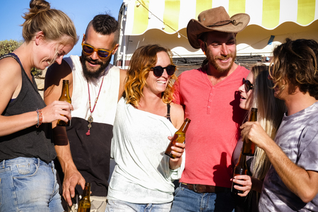 Group of friends have fun together drinking some beer outdoor near a caravan style home - traveler and young people healthy and funny lifestyle to enjoy life and friendshipの写真素材