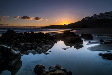 Sunrise or sunset at the ocean beach - beautiful colors and wave and sky - environment and vacation scenery place concept - landscape with coastal city and red clouds - magic light before the dayの写真素材