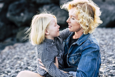 Young mother with child son looking eachother outdoor with love and fun - divorced mommy with beautiful kid hugging and smiling together forever - family concept and parents couple lovingの写真素材