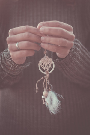 Two caucasian female hands holding a dream catcher in vintage filter colors mood - freedom and hope concept for hippy and indian people - closeupの写真素材