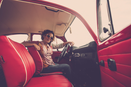 Beautiful young woman driving an old red carの写真素材