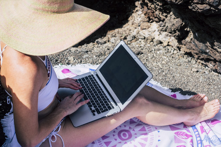 Nomadic people working on the beach. Caucasian pretty woman with laptopの写真素材