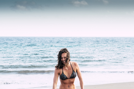 Attractive young happy caucasian woman in bikini enjoying the summer vacation with blue ocean and clear sky in background- travel and wanderlust concept for aleternative peopleの写真素材