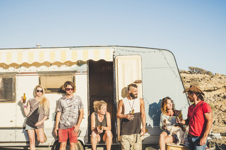 Travelers and alternative people enjoying freedom and desert outdoor - group of friends out of a old caravan for vacation and different life concept.- beautiful young men and women togetherの写真素材