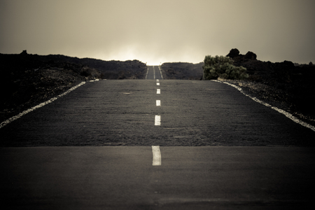 Long way road with no cars and traffic - dark tones and straight white line in the middle of the asphalt - mistery and fear concept for travelerの写真素材
