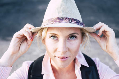 Beautiful european middle age young woman with blue green eyes looking at the camera holding a fashion hat - bright image for attractive people in outdoor leisure activityの写真素材