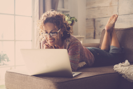 Woman smile and use an internet laptop connected to watch a movie or work easy at home in alternative office and lifestyle concept - freelance and free people with technologyの写真素材
