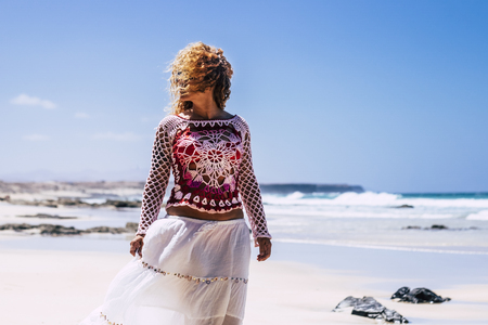 Beautiful hippy chic fashion female with long blonde curly hair outdoor enjoying the beach in summer vacation holiday - Nature in tropical place with elegant coloured adult caucasian femaleの写真素材