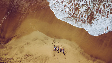 Group of friends people enjoying the beach laying on the sand - aerial top view with waves comnig,...