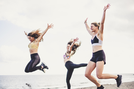 Happiness and joyful jump group of young female people in outdoor activity for healthy lifestyle together in friendship - success and team happy at the beach during summer vacationの写真素材