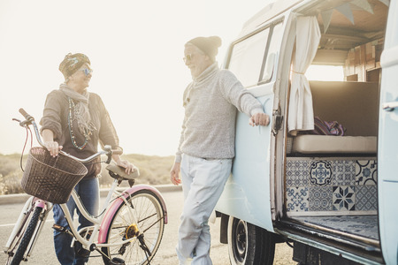 Happy people senior age couple smile and enjoy outdoor travel leisure activity together with vintage bike and van for alternative summer vacation concept - retired lifestyleの写真素材