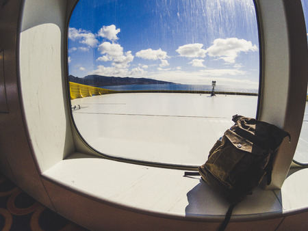 Leather trendy backpack near a windoe on ferry boat for traverl holiday summer vacation concept for people - view on beautiful island and blue sky and oceanの写真素材