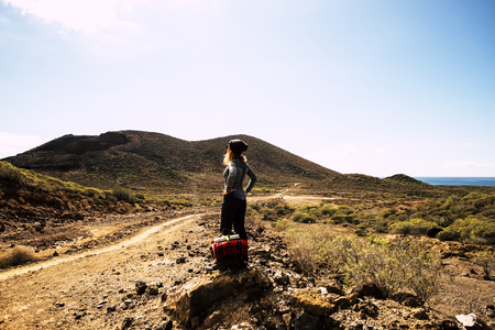 People in outdoor nature beautiful place - blonde woman standing and looking at the panorama with mountains and ocean - backpack adventure activity in outdoor scenic trekking pathの写真素材